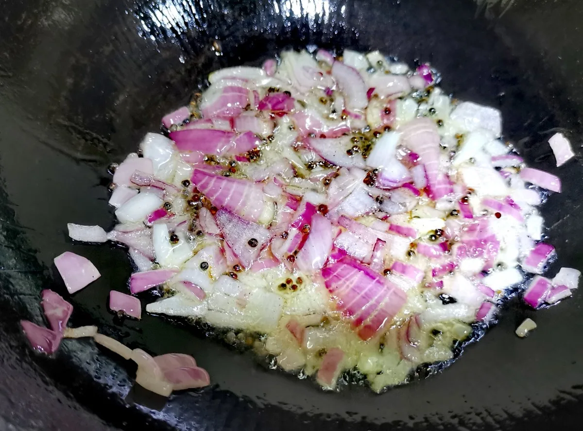 Once the mustard seeds start spluttering, add chopped onions and green chillies. Saute until the onions become translucent.
