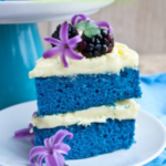 " Eggless Blue Velvet Cake Recipe!!" and "queenofrecipes.online" are written on an image with an Eggless Blue Velvet Cake.